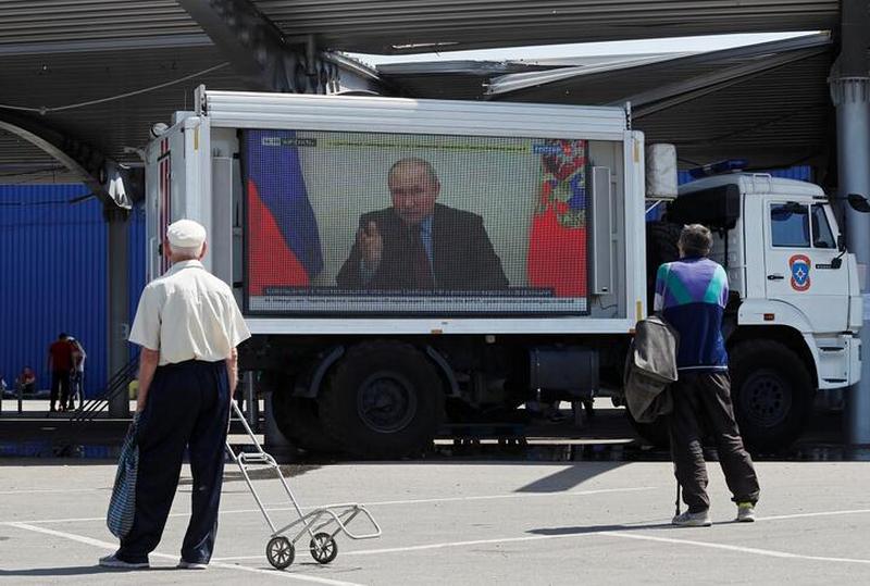 Выступление Владимира Путина на одном из российских телеканалов на автомобиле с экраном в пункте выдачи гуманитарной помощи в украинском Мариуполе 30 мая 2022 года. Фото: Reuters