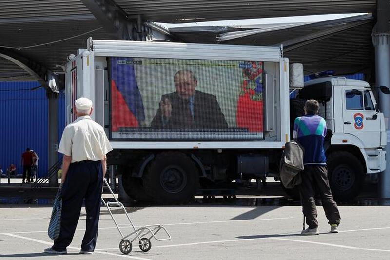 Выступление Владимира Путина на одном из российских телеканалов на автомобиле с экраном в пункте выдачи гуманитарной помощи в украинском Мариуполе 30 мая 2022 года. Фото: Reuters