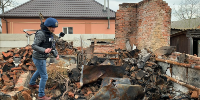 На здымку: журналіст Слава Маўрычаў працуе над рэпартажам з вызваленнага сяла Гусарвіка, красавік 2022 г. Фота Марыі Малеўскай