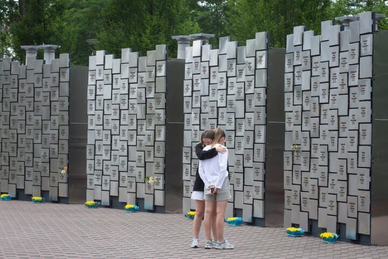 Девушки скорбят возле возведенного в центре Бучи мемориала в память о пяти сотнях гражданских, убитых российскими военными в 2022 году, Украина, 2 июля 2023 года